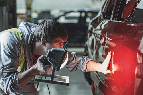An employee of the car body painting shop checks the quality