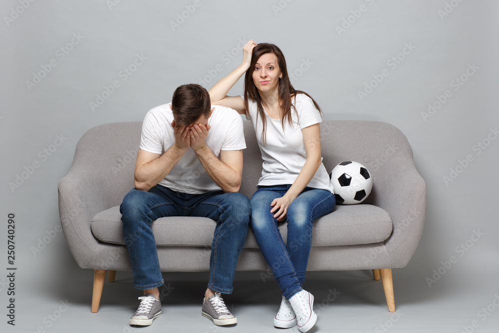 Φωτογραφία Concerned couple woman man football fans cheer up support favorite team with soccer ball covering face with hands isolated on grey background