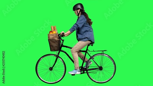 Safety first woman riding a bicycle over a green screen, looking around, wearing a helmet. No motion blur for optimal keying.
