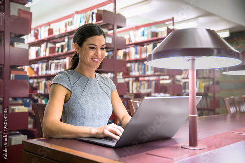 Tablou pe pânză Smiling university student at campus library, studying, researching, ambitious a