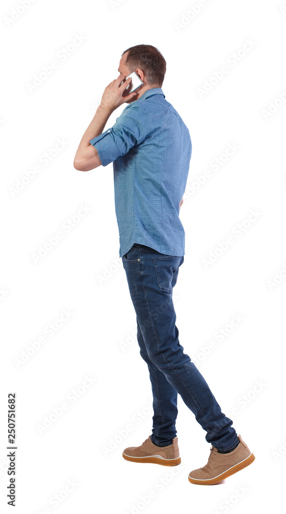 Back view of man walking with a mobile phone. Back view of man walking with a mobile phone.