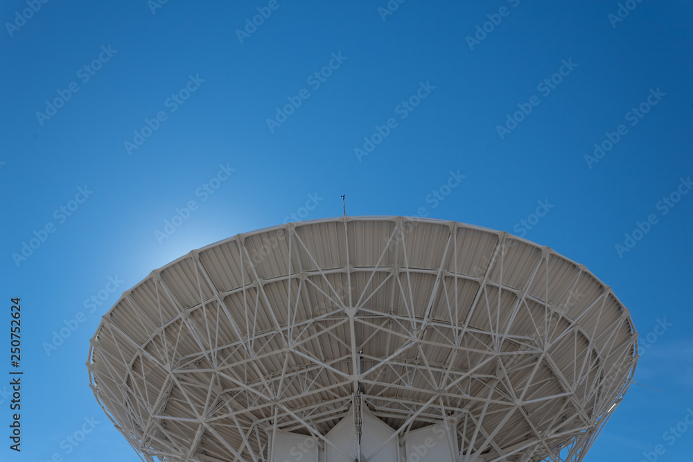 Very Large Array backlit radio astronomy observatory dish in clear sky, science technology space, horizontal aspect