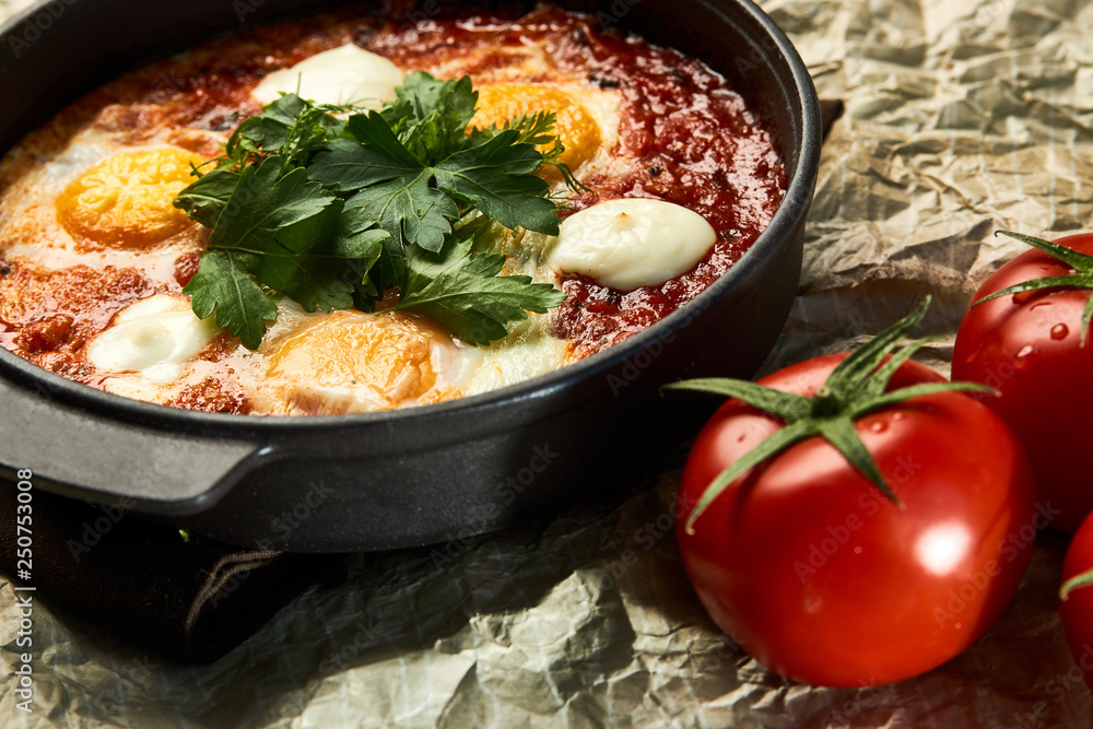 Traditional shakshuka with eggs, tomatoes and parsley in a frying pan