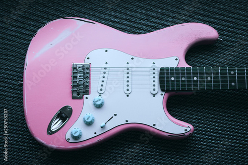 Light pink electric guitar in a purple texture background.