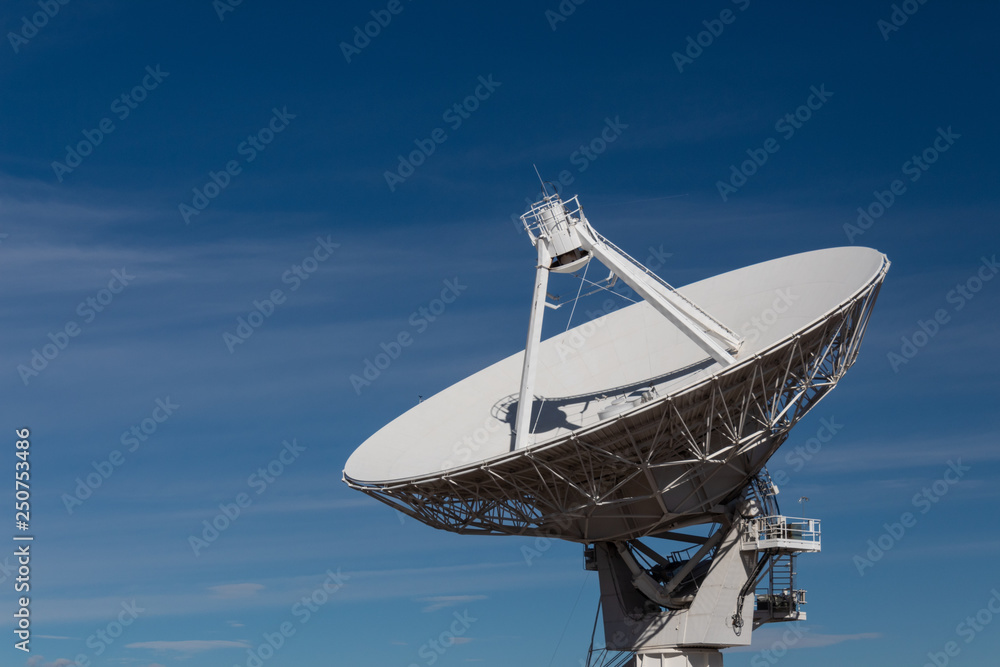 Very Large Array radio satellite dish antenna isolated against a deep blue sky, copy space, horizontal aspect Very Large Array radio satellite dish antenna isolated against a deep blue sky, copy space, horizontal aspect