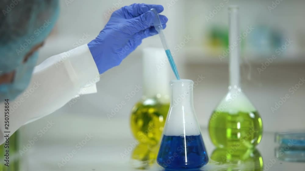 Chemist taking blue substance sample from flask, washing agent analysis, test Chemist taking blue substance sample from flask, washing agent analysis, test