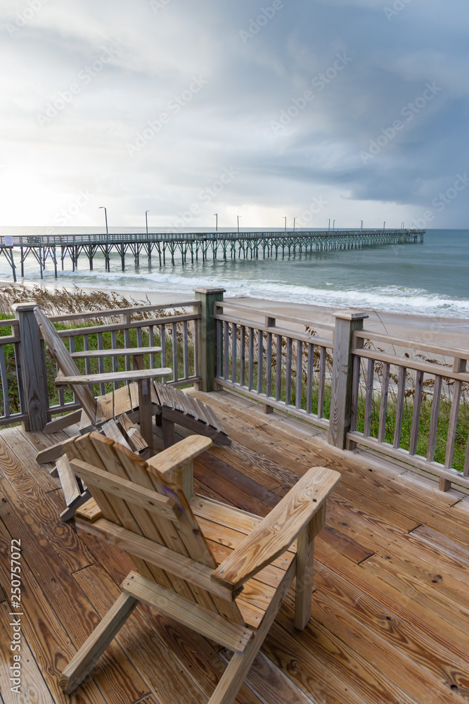 Adirondack chairs overlooking an ocean pier on a North Carolina beach.