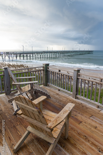 Obraz na płótnie Adirondack chairs overlooking an ocean pier on a North Carolina beach. w salonie