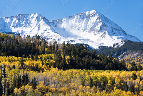 Early autumn snow covers a rugged mountain range in Southwestern Colorado. Aspen groves with the changing season  add to the color of the fall season.