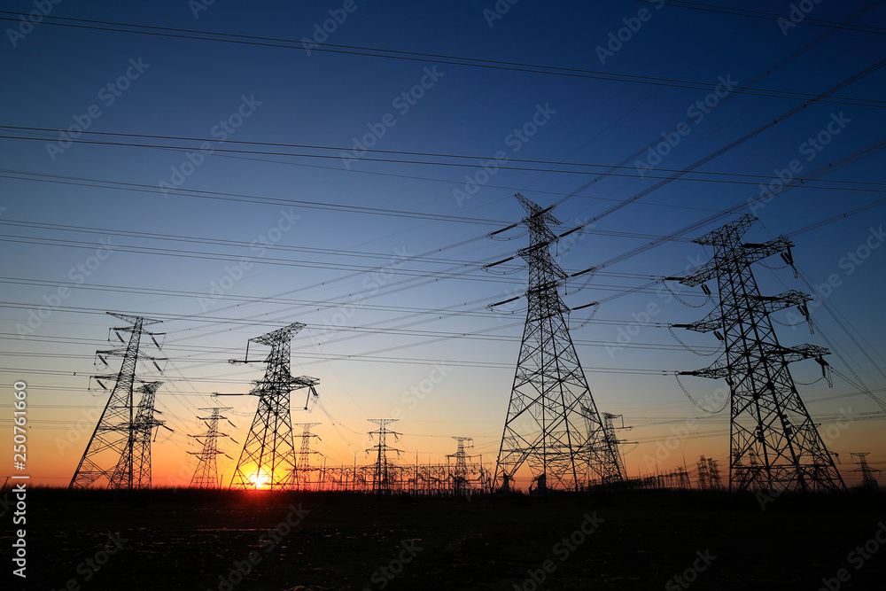 A high-voltage tower in the setting sun against the sky