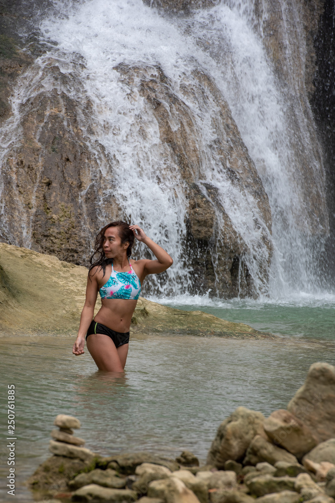 Filipino girl yoga posing at tropical waterfall 