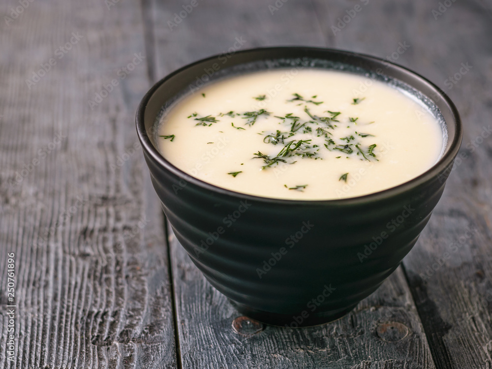 A free-standing bowl of cauliflower cream soup on a black table. A free-standing bowl of cauliflower cream soup on a black table.