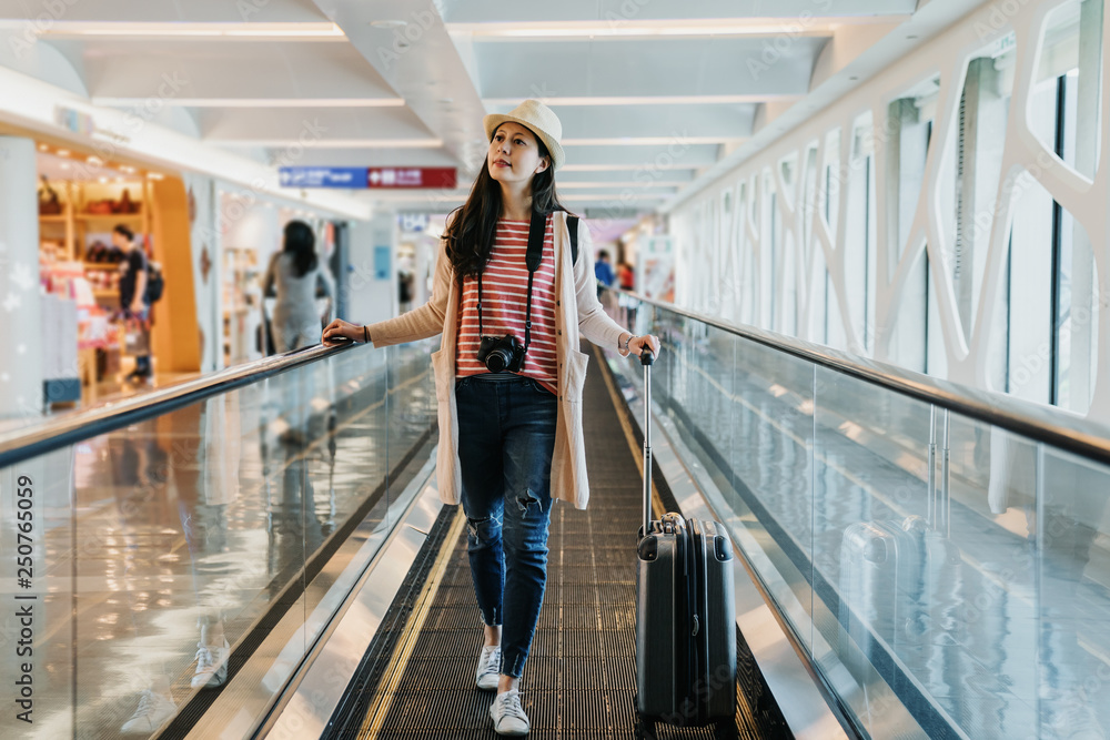 Φωτογραφία asian tourist elegant woman walking on the moving walkway at the airport with black suitcase