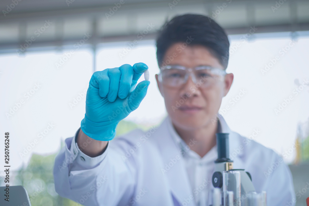 Scientist holding the pill and he extended his hand forward Scientist holding the pill and he extended his hand forward