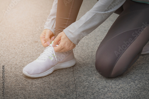 Closeup of woman tying shoe laces. Female sport fitness runner getting ready for jogging outdoors.