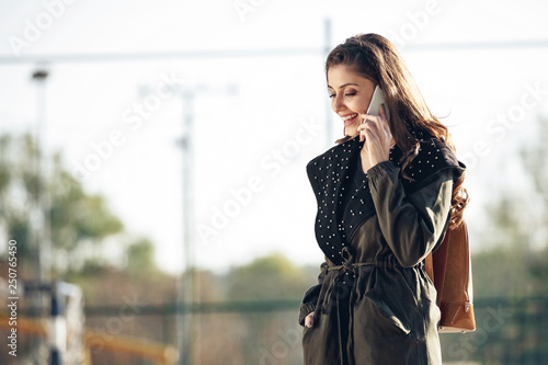Young happy woman talking on mobile phone outdoors.