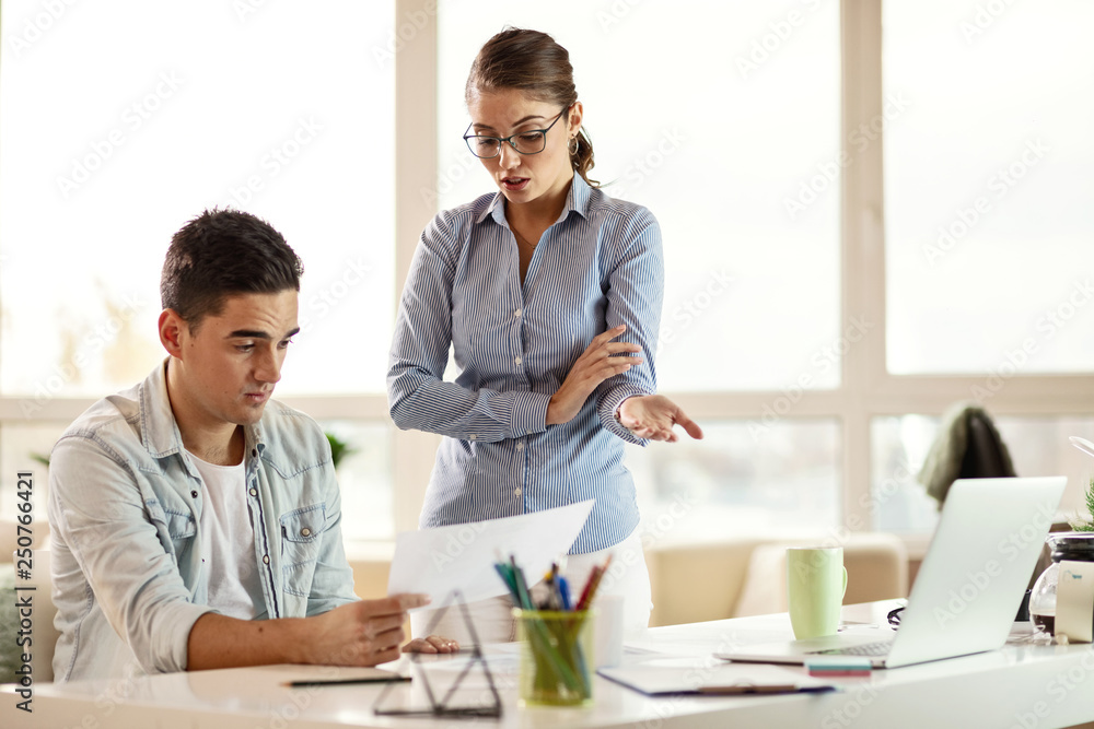Young businesswoman scolding her male coworker on a meeting in the office.
