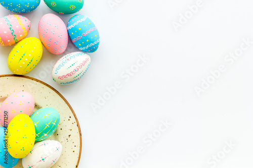 Festive Easter table. Colorful Easter eggs on plate on white background top view copy space