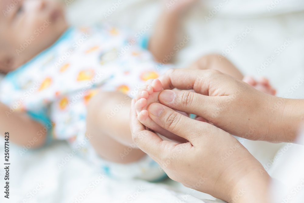 Baby boy foot massage by mom on white blanket Baby boy foot massage by mom on white blanket