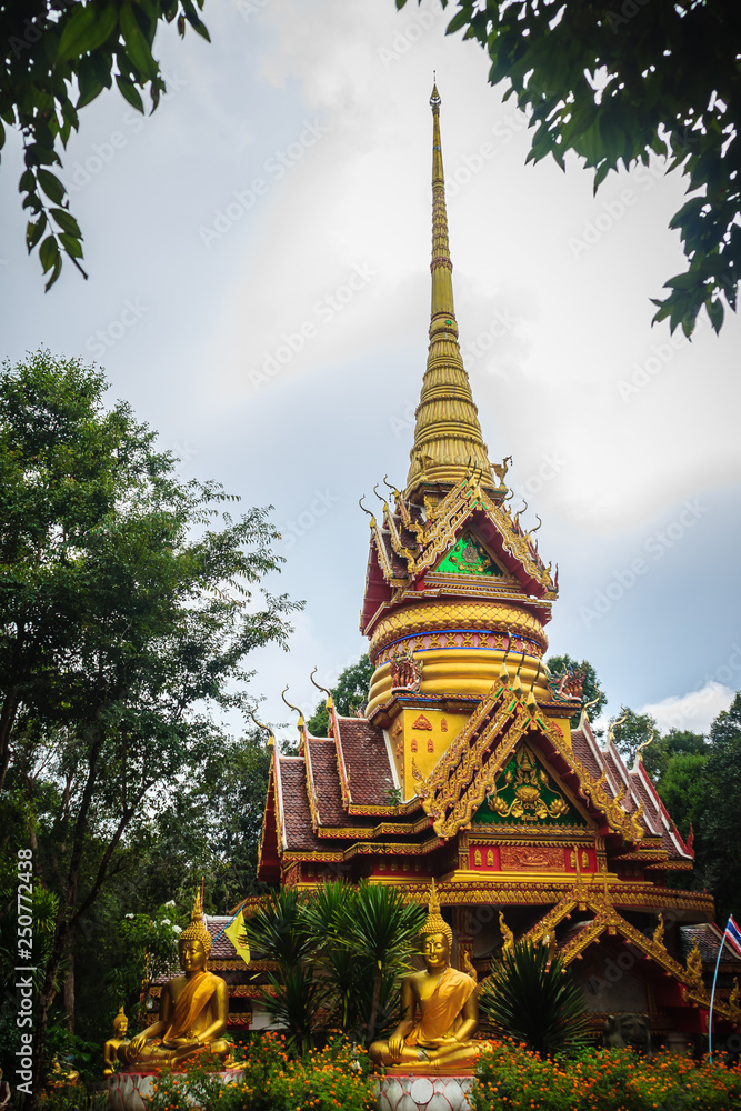 Fototapeta premium Beautiful golden pagoda with decorative Thai style fine art at public Buddhist Wat Phu Phlan Sung, Nachaluay, Ubon Ratchathani, Thailand.