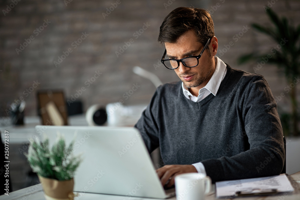 Male entrepreneur typing an e-mail while working on laptop in the office. Male entrepreneur typing an e-mail while working on laptop in the office.