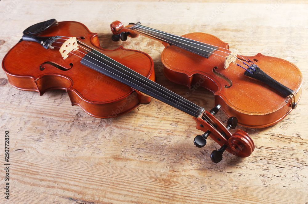 Fototapeta premium Two violins on a wooden table