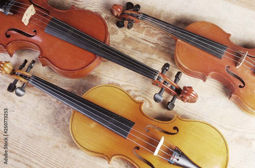 Fototapeta premium Three violins on wooden texture