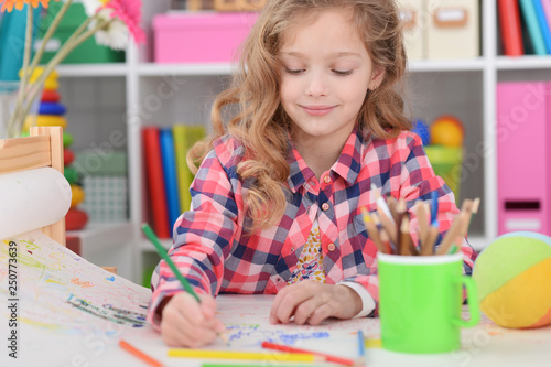 Portrait of cute curly girl drawing colored pencils at home
