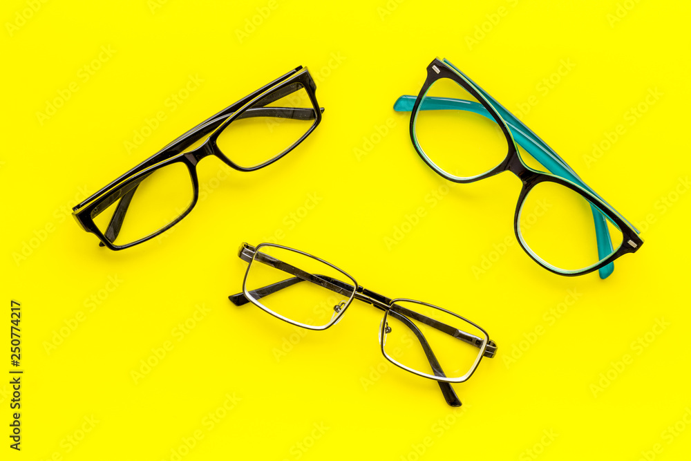 Set of glasses with transparent lenses on yellow background top view Set of glasses with transparent lenses on yellow background top view