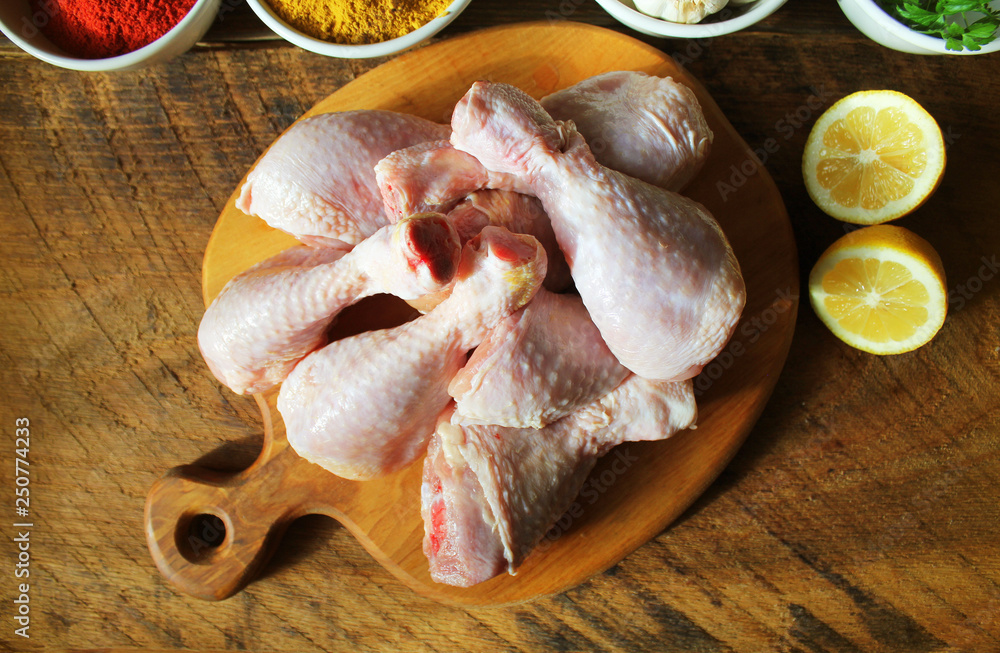 Raw uncooked chicken legs, drumsticks on cutting board, meat with ingredients for cooking