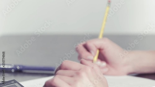Woman writing numbers with a pencil by a calculator