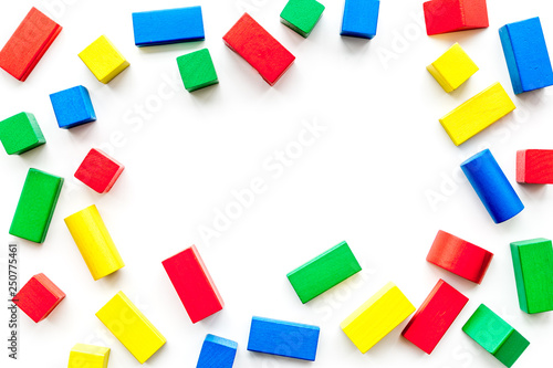 Construction game for kids. Wooden building blocks, toy bricks on white background top view copy space frame