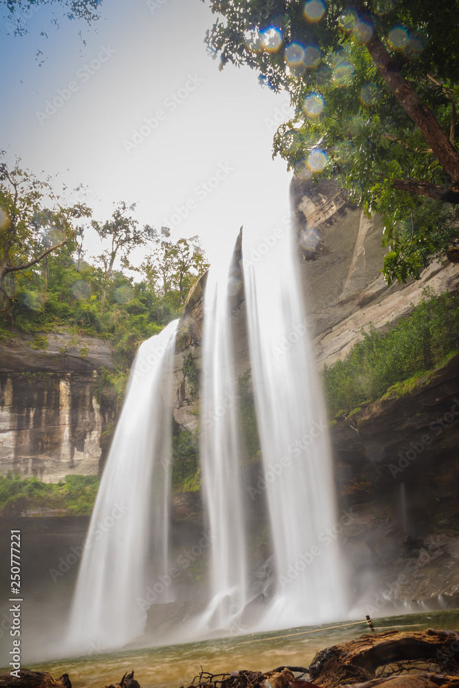 Naklejka premium Huai Luang Waterfall, also known as Namtok Huai Luang or Namtok Bak Teo. The waterfall is plunging down three steps from an elevation of 30 meters with pool, white beach and turquoise colored water.