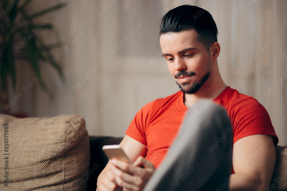 Man Holding Smartphone Relaxing on a Sofa at Home Man Holding Smartphone Relaxing on a Sofa at Home