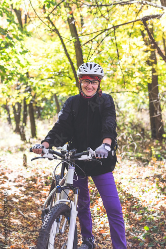 Cute young woman on a bicycle in the autumn forest