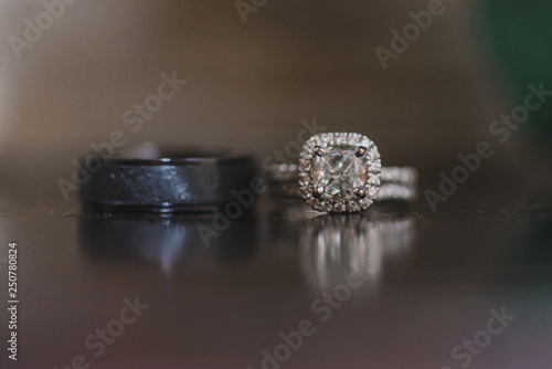 Silver and black wedding rings with diamonds on reflective surface