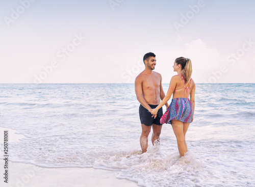 Young couple holding their hands at the beach © Guajillo studio