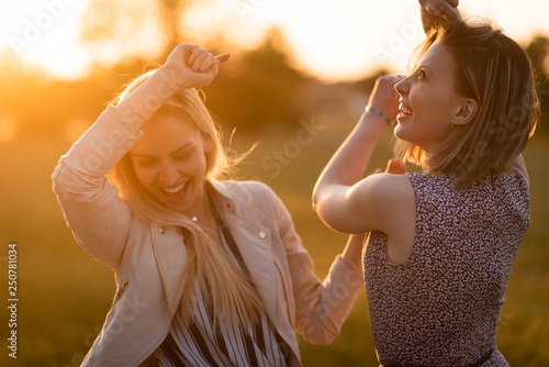 Joyful young women dancing during sunset © Martinan