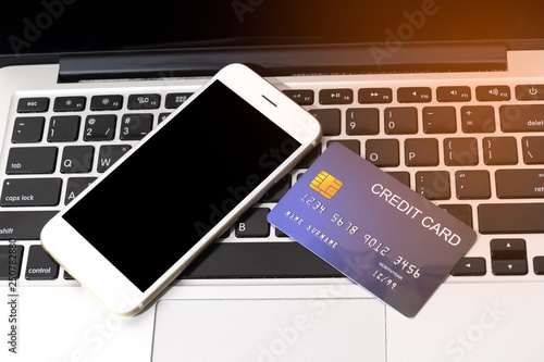 credit card put beside mobile phone on laptop keyboard for preparing to pay with flare