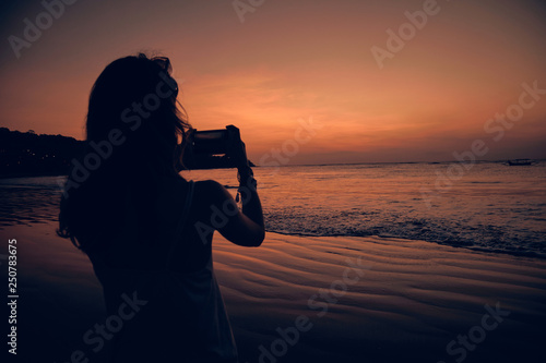 Woman using cellphone on a tropical ocean beach.