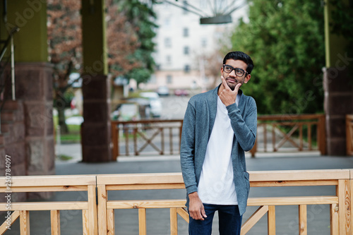 Stylish indian man at glasses wear casual posed outdoor and thinking.