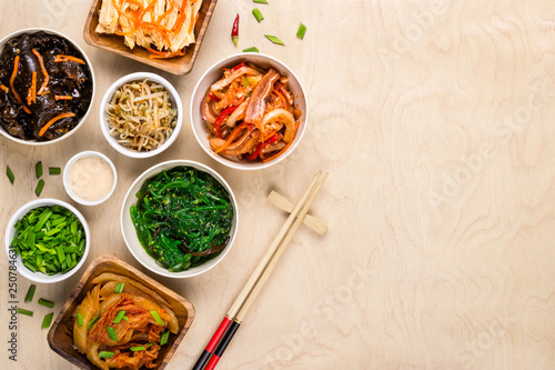 Assorted korean food and chopsticks on wooden background photo