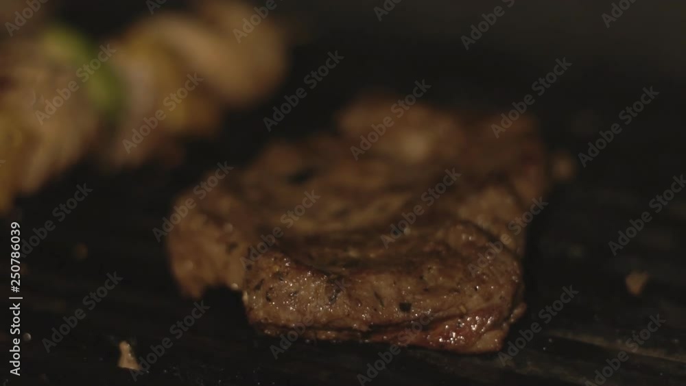 Macro piece of pork or beef meat on barbecue grill, steak or beefsteak is cooking on cafe's kitchen. Meat is cooked on bbq grill in masonry brick oven over charcoals in restaurant in slow motion. Macro piece of pork or beef meat on barbecue grill, steak or beefsteak is cooking on cafe's kitchen. Meat is cooked on bbq grill in masonry brick oven over charcoals in restaurant in slow motion.