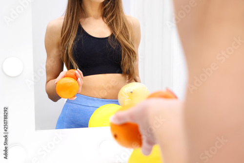Owocowa dieta w walce z cellulitem. Szczupła kobieta przegląda się w lustrze.
