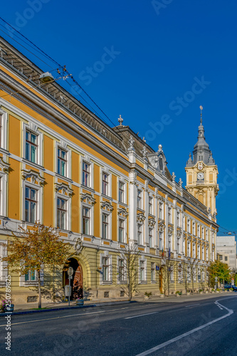 Cluj-Napoca City Hall on a sunny summer day with blue sky in Romania. It features a Viennese baroque facade with a corner clock tower