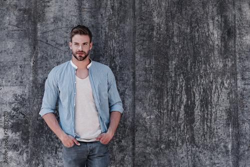 This is what handsome looks like. Sexy brown-haired man with blue eyes standing isolated over grey background