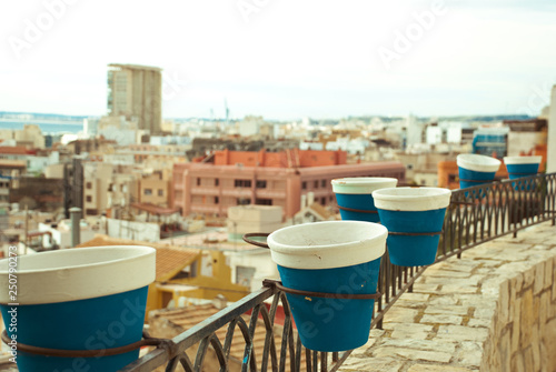 Empty blue and white flower pots in macro and view on the city and sea. © Etnika