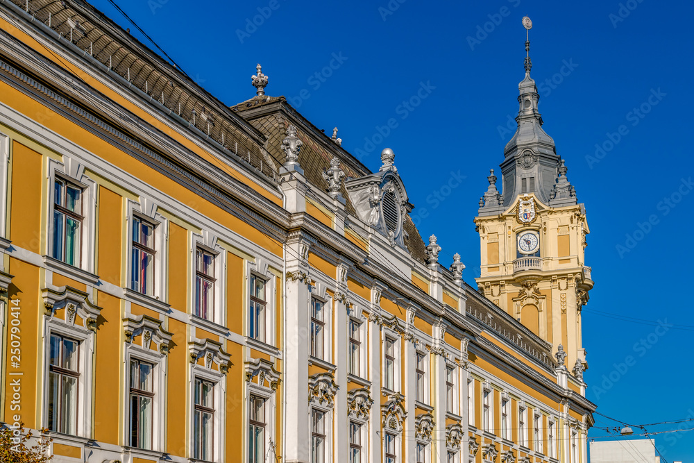 Cluj-Napoca City Hall  on a sunny summer day with blue sky in Romania. It features a Viennese baroque facade with a corner clock tower