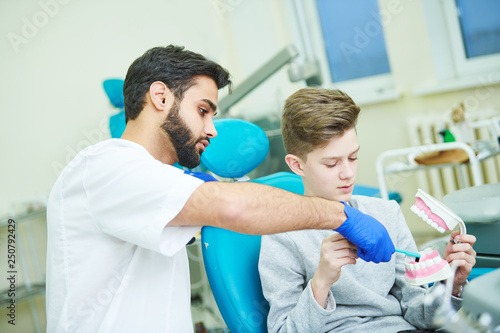 teeth care. Dentist with young patient training to clean