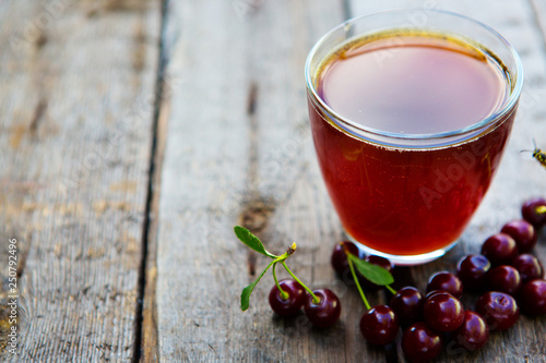 Homemade cherry juice in glass with freshcherry on wooden table. Fresh fruit drink photo